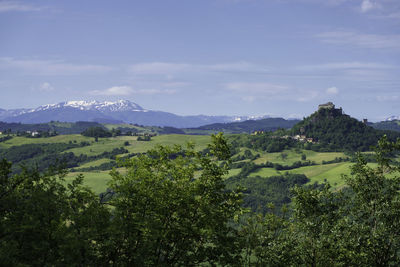 Scenic view of green landscape and mountains against sky