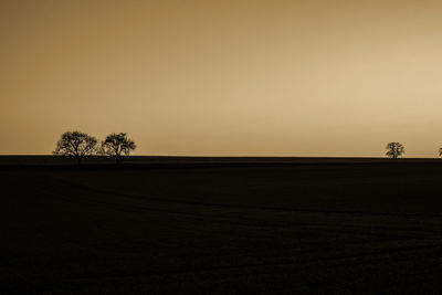 Scenic view of silhouette field against clear sky during sunset