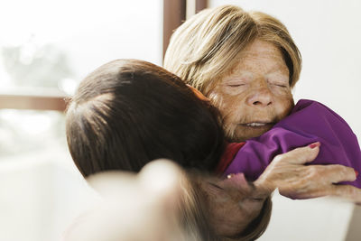 Healthcare giver hugging senior woman at home