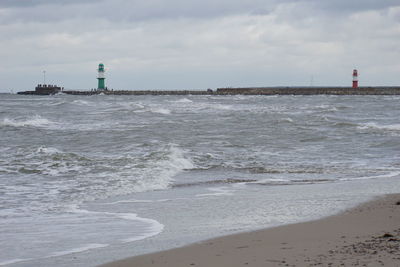 Lighthouse by sea against sky