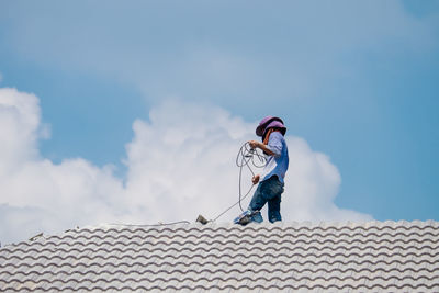 Low angle view of man on roof against sky