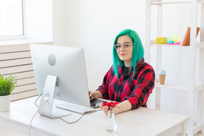 Young woman using phone while sitting on table