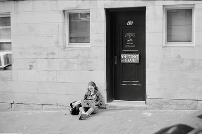 Full length of woman sitting on street in city