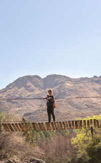 Full length of man standing on mountain against clear sky