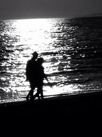 Silhouette people in sea at sunset