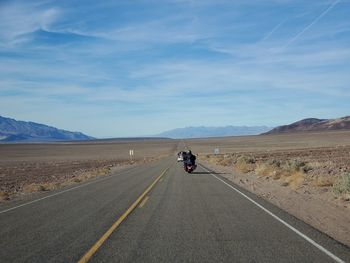 People riding motorcycle on road against sky