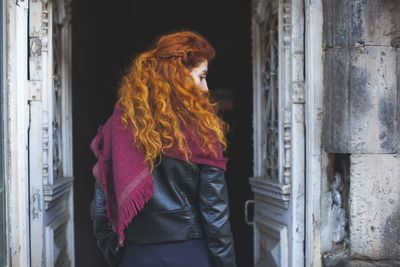 Rear view of redhead woman standing at doorway