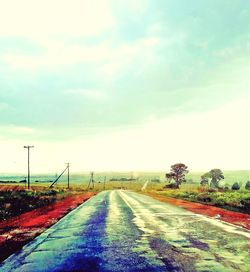 Road amidst field against sky