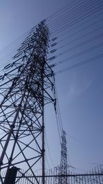 Low angle view of electricity pylon against blue sky