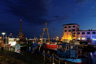 Sailboats moored at harbor against sky at night