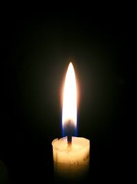 Close-up of illuminated candle over black background