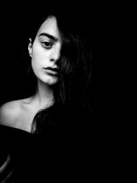 Close-up portrait of young woman against black background