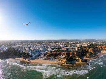 Aerial view of city and sea against blue sky