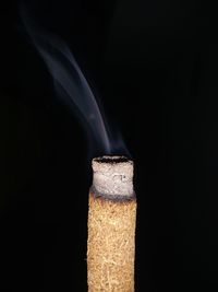 Close-up of burning candle against black background