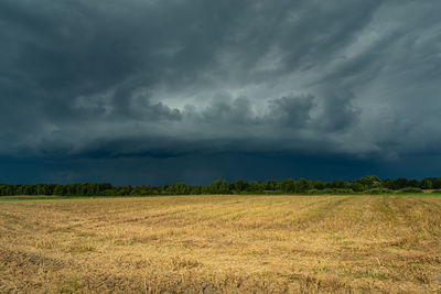 Storm supercell in gray sky over agricultural fields