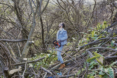 Man standing by bare tree in forest