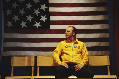 Man sitting on chair against american flag