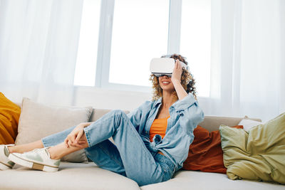 Young woman using mobile phone while sitting on bed at home