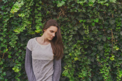 Young woman standing against plants