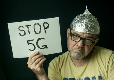 Portrait of man holding smart phone against black background