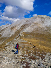 Full length of person on rock in mountains against sky