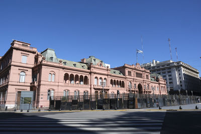 Road by buildings against clear blue sky