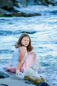 Portrait of happy girl sitting in sea