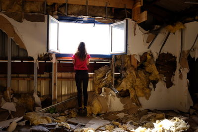 Full length rear view of woman standing in abandoned room