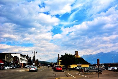 Cars on road against cloudy sky