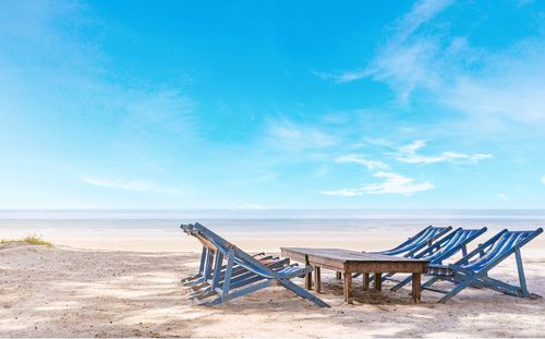 Empty chair on beach against sky