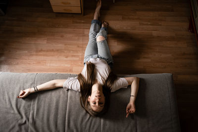 High angle portrait of woman lying on hardwood floor