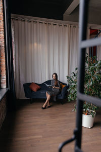 Rear view of woman sitting on bed at home