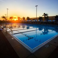 Swimming pool against sky during sunset