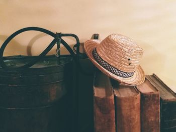 Close-up of wicker hat on book against wall