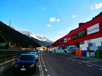 Cars on road by mountain against blue sky