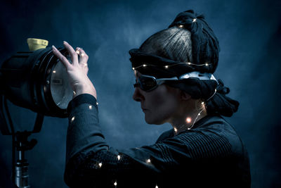 Side view of woman holding strobe light