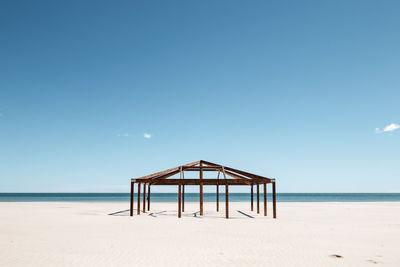 Gazebo at beach against clear blue sky