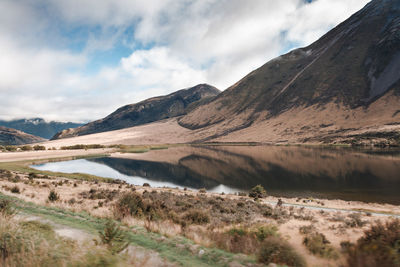 Scenic view of lake and mountains against cloudy sky