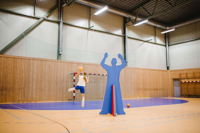 Female handball player aiming with ball in sports court