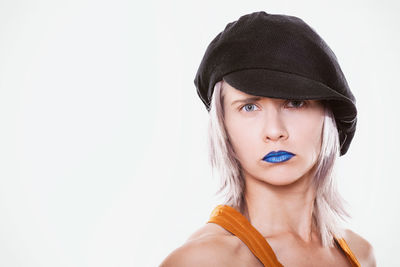 Portrait of beautiful young woman wearing hat against white background