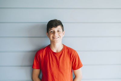 Portrait of a smiling young man standing against wall