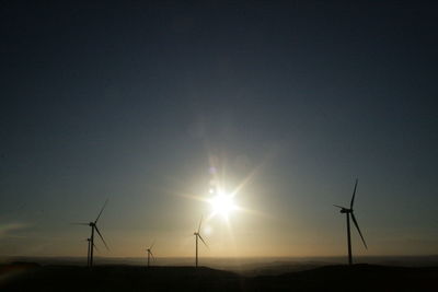 Wind turbines on landscape at sunset