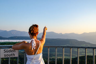Rear view of woman pointing at mountains