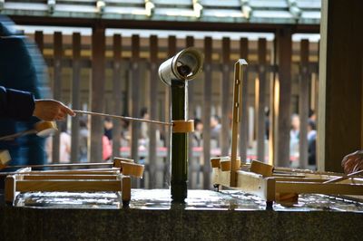 Cropped hand filling water in bamboo dipper at shrine