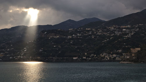 Scenic view of sea by mountains against sky