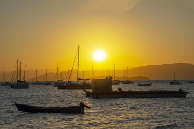 Sailboats moored in marina at sunset