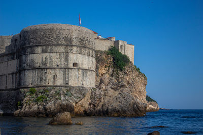 Castle by sea against clear blue sky