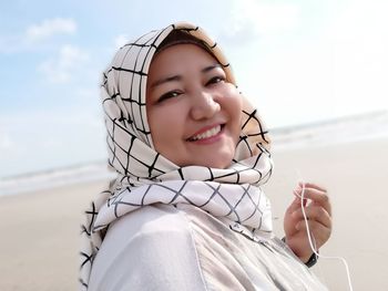 Portrait of smiling woman wearing hijab at beach