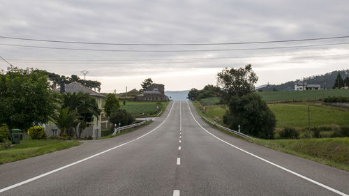 Road by trees against sky