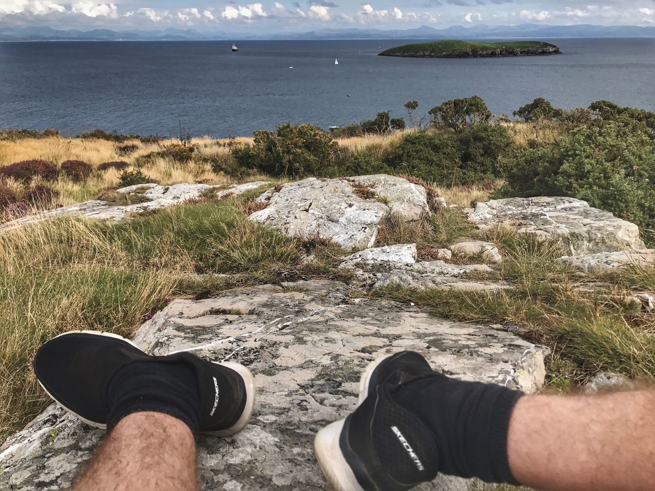 sea, nature, day, one person, rock - object, water, grass, beach, scenics, outdoors, human leg, men, low section, tranquility, real people, beauty in nature, horizon over water, landscape, human body part, one man only, sky, people